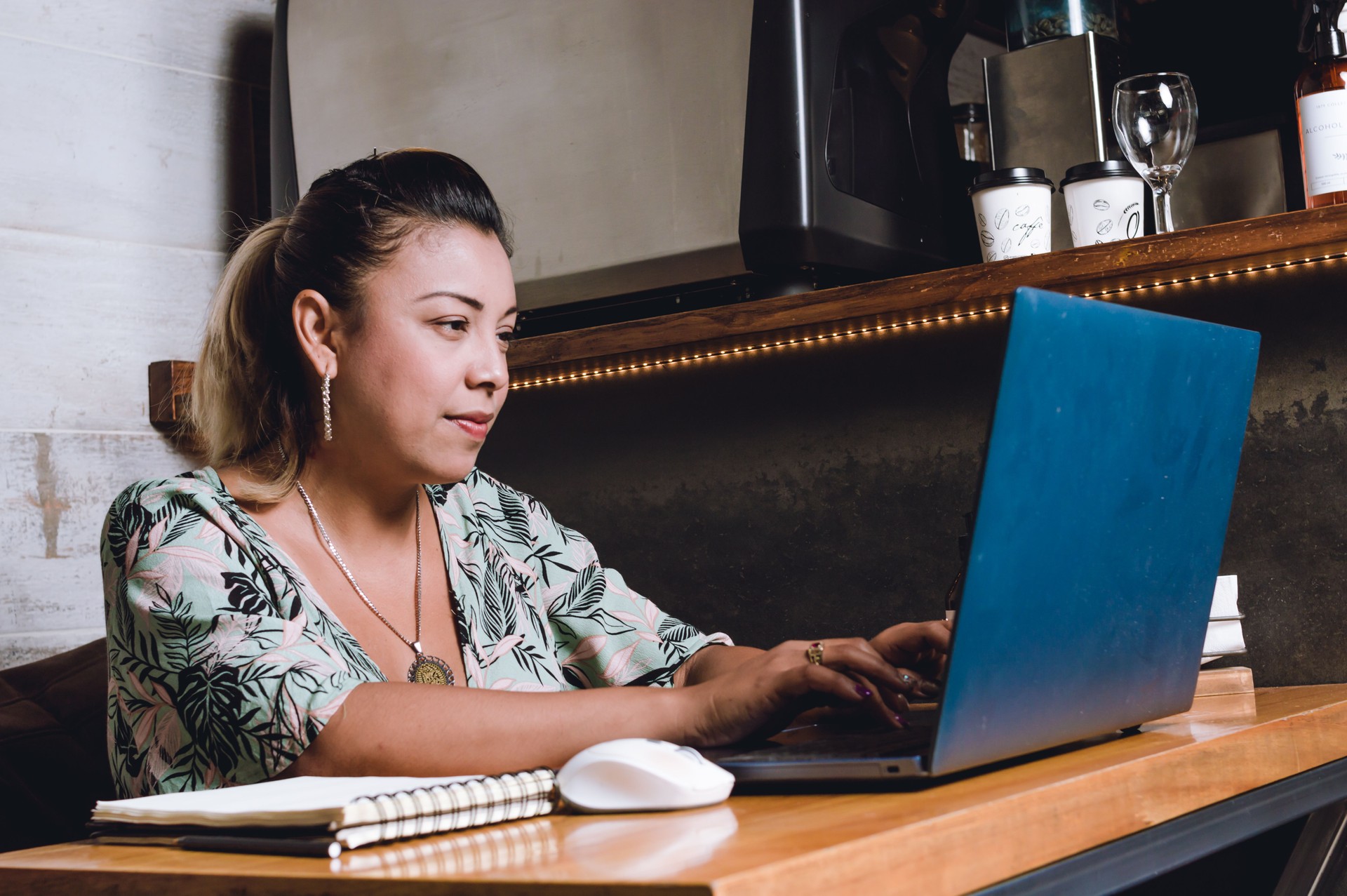 young latina freelancer with her computer using a cafeteria as her office