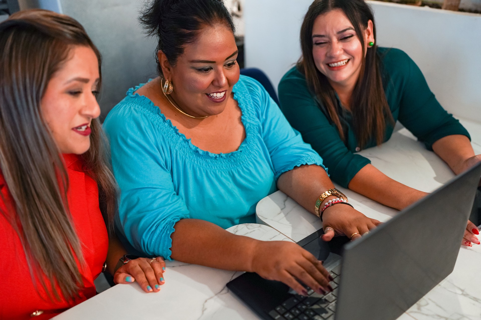 Latin businesswomen working together using laptop in co-working space